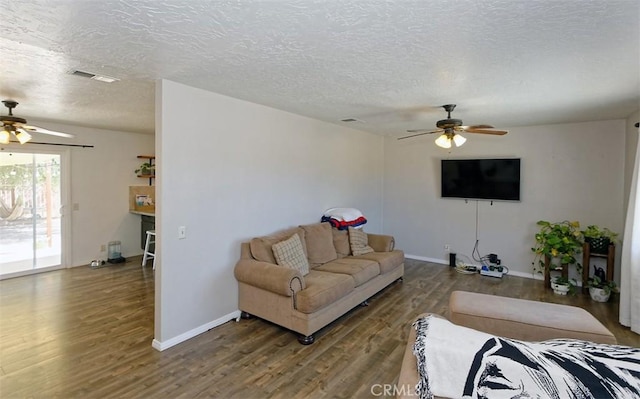 living room featuring ceiling fan, a textured ceiling, and dark hardwood / wood-style flooring