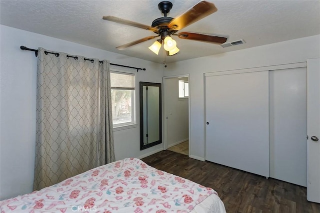 bedroom featuring ceiling fan, a closet, dark hardwood / wood-style floors, and a textured ceiling