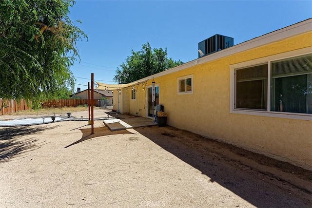 exterior space featuring a patio area, fence, central AC, and stucco siding