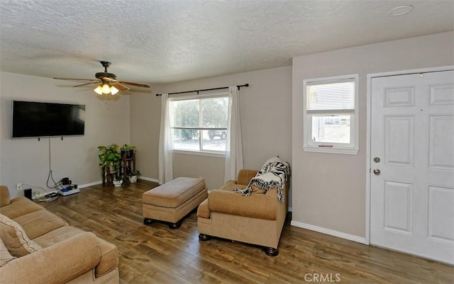 living room featuring ceiling fan, dark hardwood / wood-style flooring, and a textured ceiling