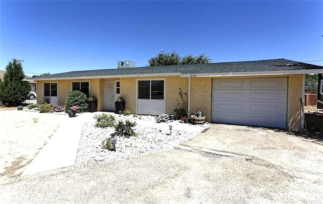 ranch-style home featuring an attached garage, driveway, and stucco siding