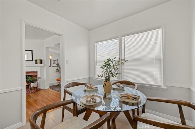 dining space with a brick fireplace and hardwood / wood-style floors