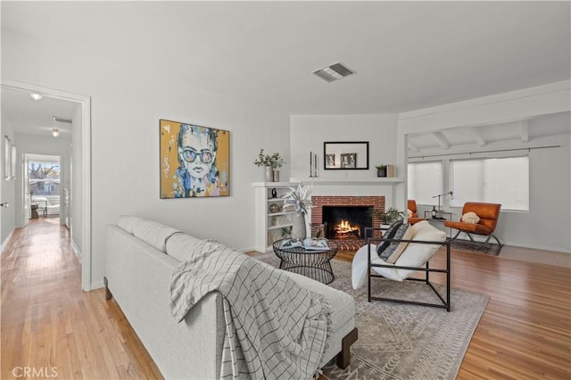 living room with a brick fireplace and light hardwood / wood-style flooring