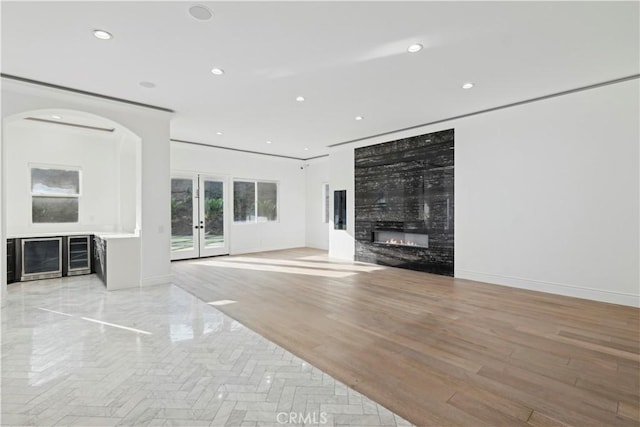 unfurnished living room featuring light hardwood / wood-style flooring, a high end fireplace, and french doors