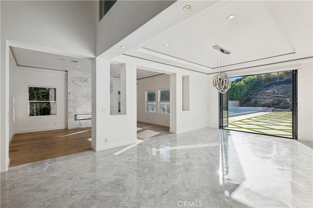 interior space with a tray ceiling, a high end fireplace, and a high ceiling