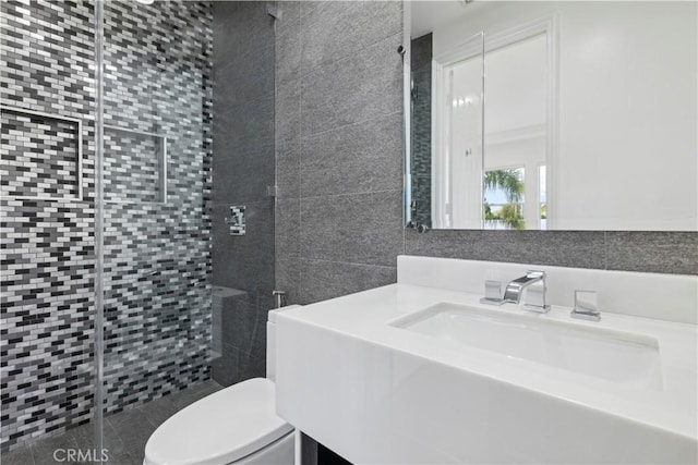 bathroom featuring vanity, tiled shower, tile walls, and toilet