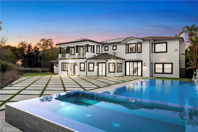 pool at dusk with a patio area