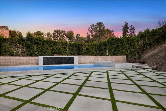 pool at dusk featuring a patio area