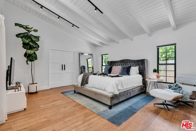 bedroom featuring beamed ceiling, track lighting, high vaulted ceiling, and light hardwood / wood-style flooring