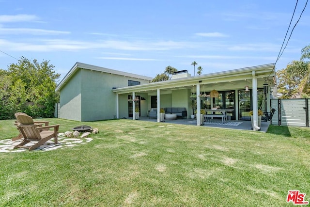 rear view of house with a patio area, a lawn, and an outdoor living space with a fire pit