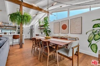 dining area featuring lofted ceiling with beams and light hardwood / wood-style floors