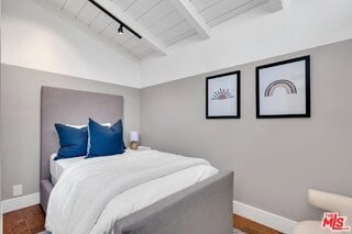 bedroom featuring vaulted ceiling with beams, wood-type flooring, wooden ceiling, and track lighting