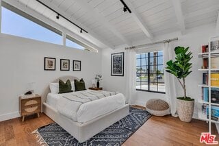 bedroom with wood ceiling, wood-type flooring, lofted ceiling with beams, and track lighting