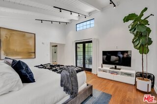 bedroom with beamed ceiling, wood-type flooring, rail lighting, and french doors