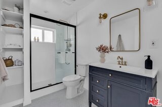 bathroom with vanity, a shower with door, and toilet