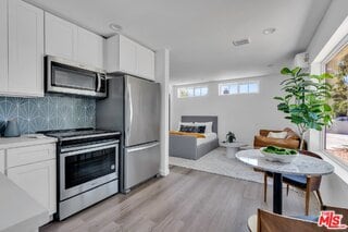 kitchen with light hardwood / wood-style flooring, white cabinets, and appliances with stainless steel finishes