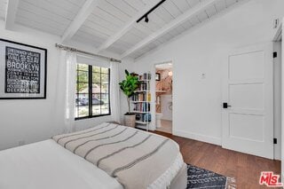 bedroom featuring dark hardwood / wood-style floors, ensuite bathroom, track lighting, lofted ceiling with beams, and wooden ceiling