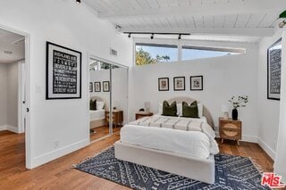 bedroom featuring hardwood / wood-style flooring, vaulted ceiling with beams, rail lighting, and wooden ceiling