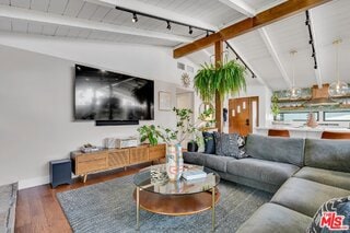 living room with dark wood-type flooring, lofted ceiling with beams, and rail lighting