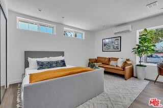 bedroom with a wall mounted AC and light wood-type flooring