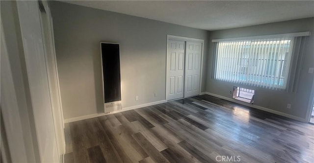 unfurnished bedroom with dark wood-type flooring and a closet