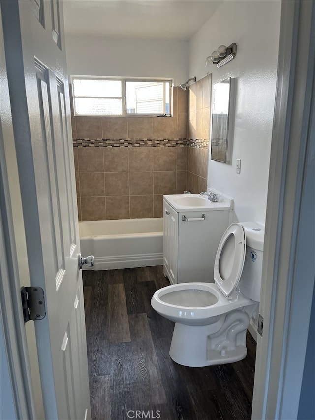 full bathroom with tiled shower / bath combo, wood-type flooring, vanity, and toilet