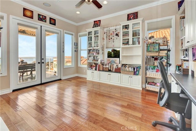 office space featuring light hardwood / wood-style flooring, ceiling fan, a water view, ornamental molding, and french doors