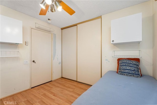 bedroom with ceiling fan, a closet, light hardwood / wood-style flooring, and a textured ceiling