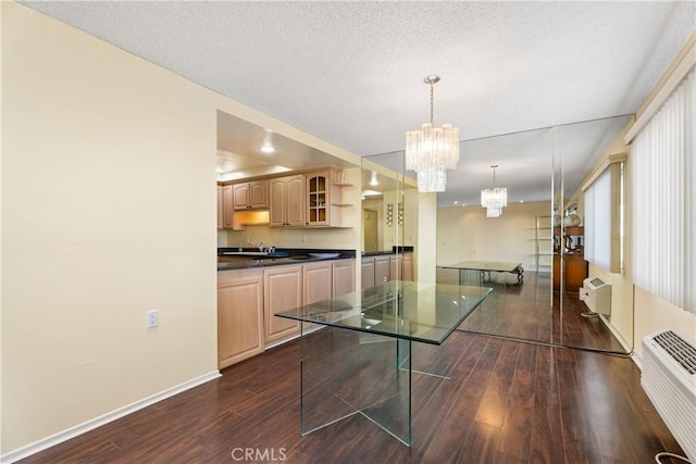 kitchen with dark wood-type flooring, hanging light fixtures, a wall mounted AC, a notable chandelier, and light brown cabinetry