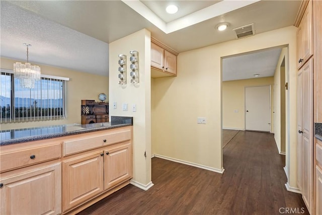 kitchen with light brown cabinetry, hanging light fixtures, dark wood-type flooring, and an inviting chandelier