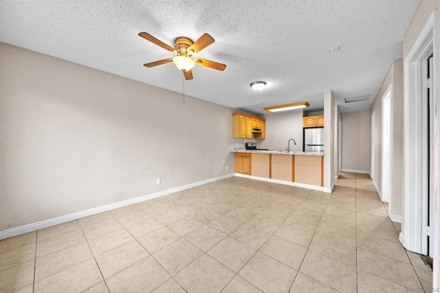 unfurnished living room featuring light tile patterned flooring, ceiling fan, sink, and a textured ceiling