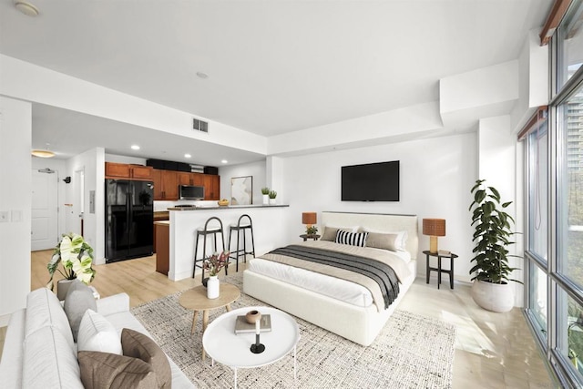 bedroom with multiple windows and black fridge