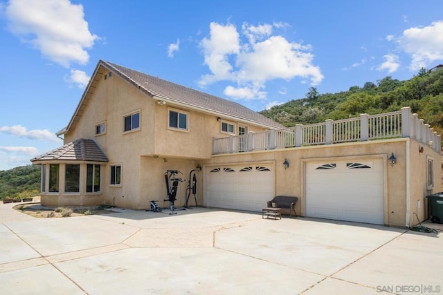 rear view of property featuring a garage and a balcony