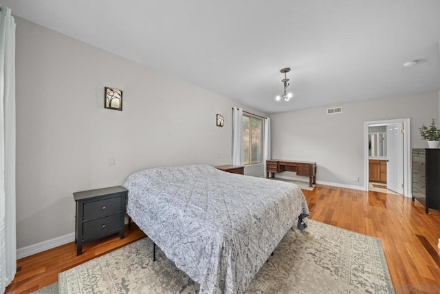 bedroom featuring ensuite bathroom and light hardwood / wood-style floors