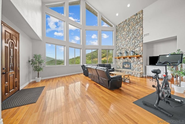 exercise area with hardwood / wood-style flooring, a fireplace, and a high ceiling