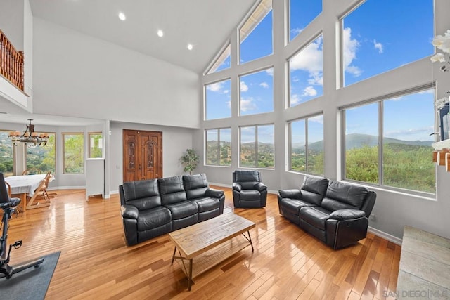 living room with an inviting chandelier, light hardwood / wood-style floors, high vaulted ceiling, and a mountain view