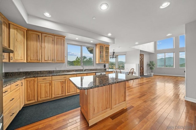 kitchen featuring dark stone countertops, sink, light wood-type flooring, and a kitchen island