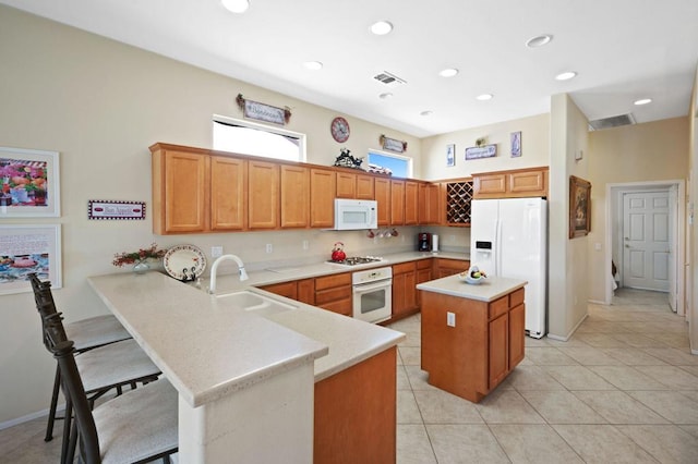 kitchen featuring sink, white appliances, a breakfast bar, a kitchen island, and kitchen peninsula