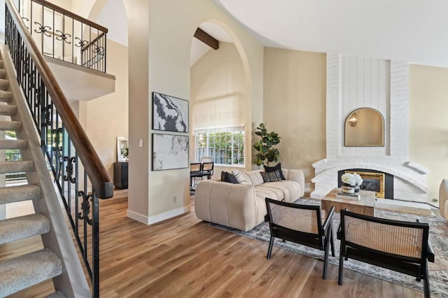 living room featuring wood-type flooring, vaulted ceiling with beams, and a fireplace