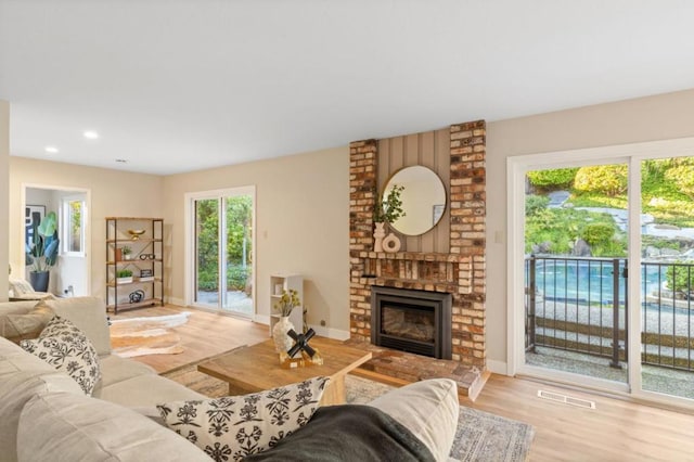 living room featuring a brick fireplace and light hardwood / wood-style floors