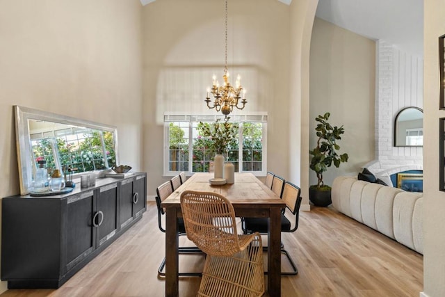 dining space with an inviting chandelier, light hardwood / wood-style flooring, and a high ceiling