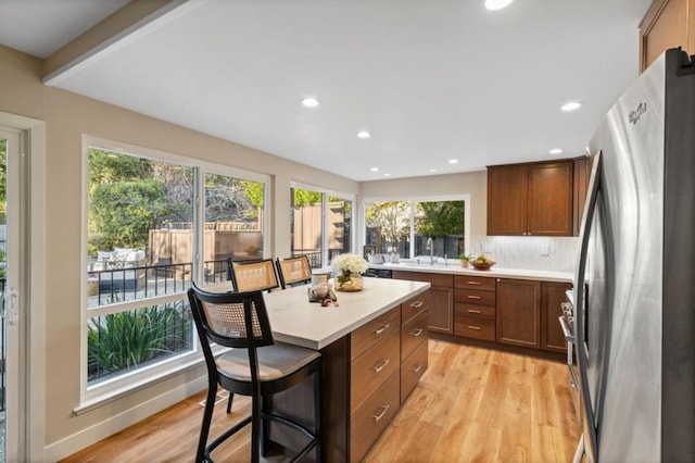 kitchen with stainless steel refrigerator, a healthy amount of sunlight, a kitchen breakfast bar, and a kitchen island