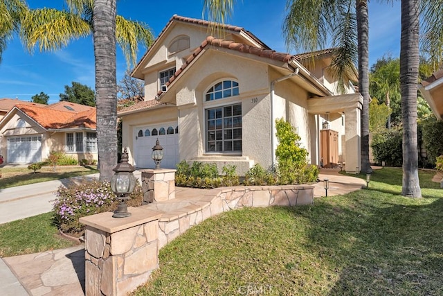 mediterranean / spanish-style house with a garage and a front lawn