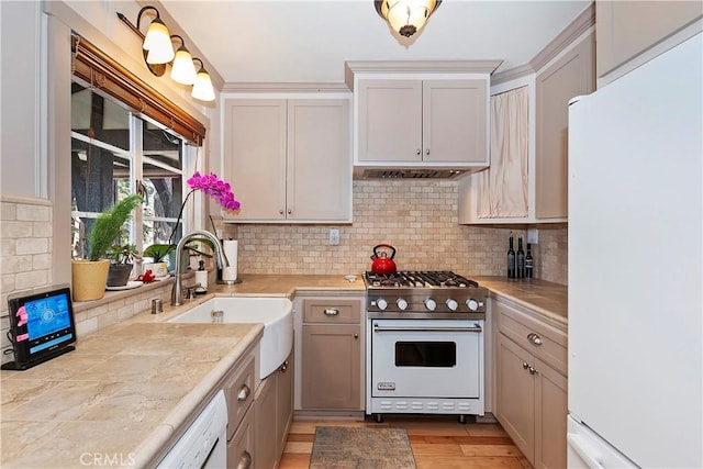 kitchen with white refrigerator, light hardwood / wood-style floors, range with gas cooktop, and decorative backsplash