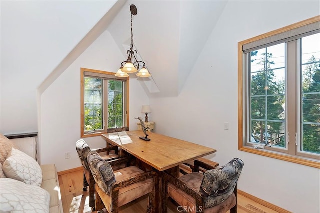 dining area featuring vaulted ceiling, hardwood / wood-style floors, and a notable chandelier