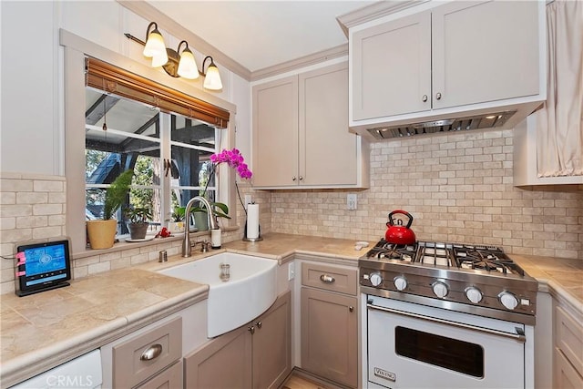 kitchen with sink, luxury stove, white cabinets, and decorative backsplash