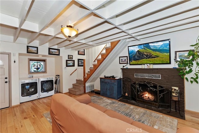 living room with beam ceiling, washer and clothes dryer, and light hardwood / wood-style floors