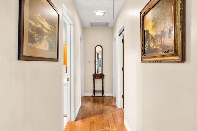 corridor featuring a textured ceiling and light wood-type flooring