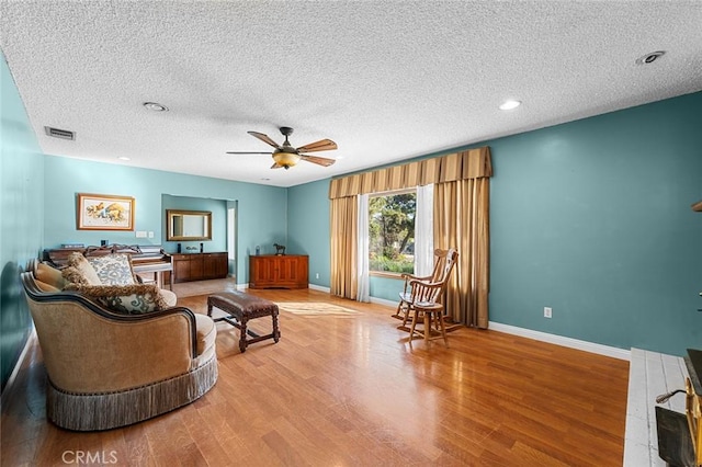 living room with hardwood / wood-style floors, a textured ceiling, and ceiling fan