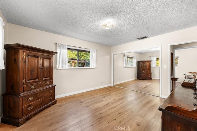 bedroom with a closet, light hardwood / wood-style flooring, and a textured ceiling